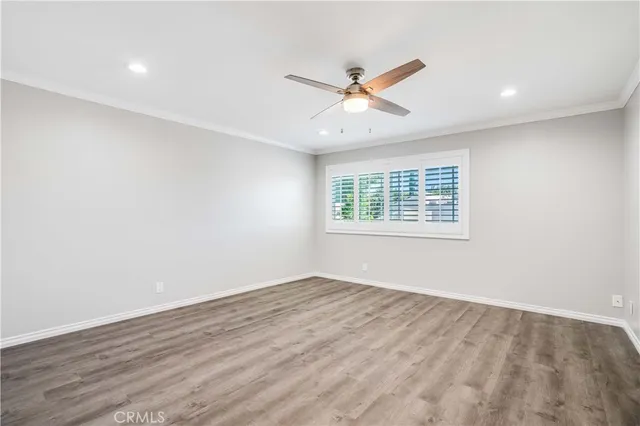 an empty room with wooden floor windows and fan