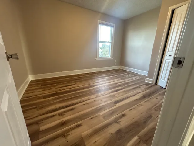 a view of empty room with window and wooden floor