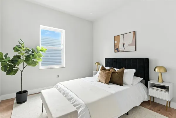 a bedroom with a bed a potted plant and a window