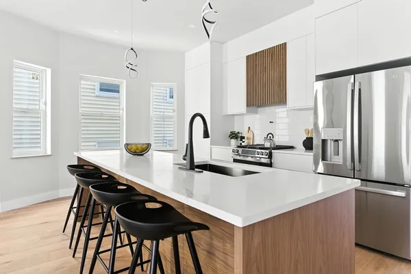 a kitchen with stainless steel appliances kitchen island a table chairs in it and wooden floors