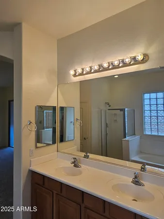 a bathroom with a vanity a sink a mirror and a shower