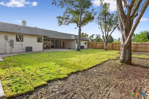 a view of a house with a yard and large tree