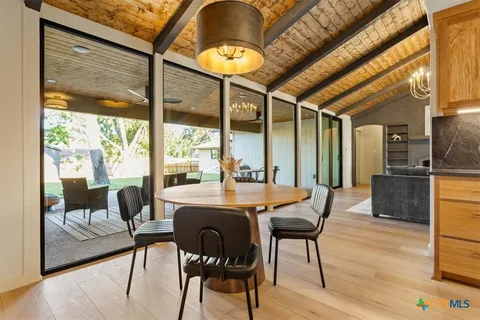 a view of a dining room with furniture a chandelier and wooden floor