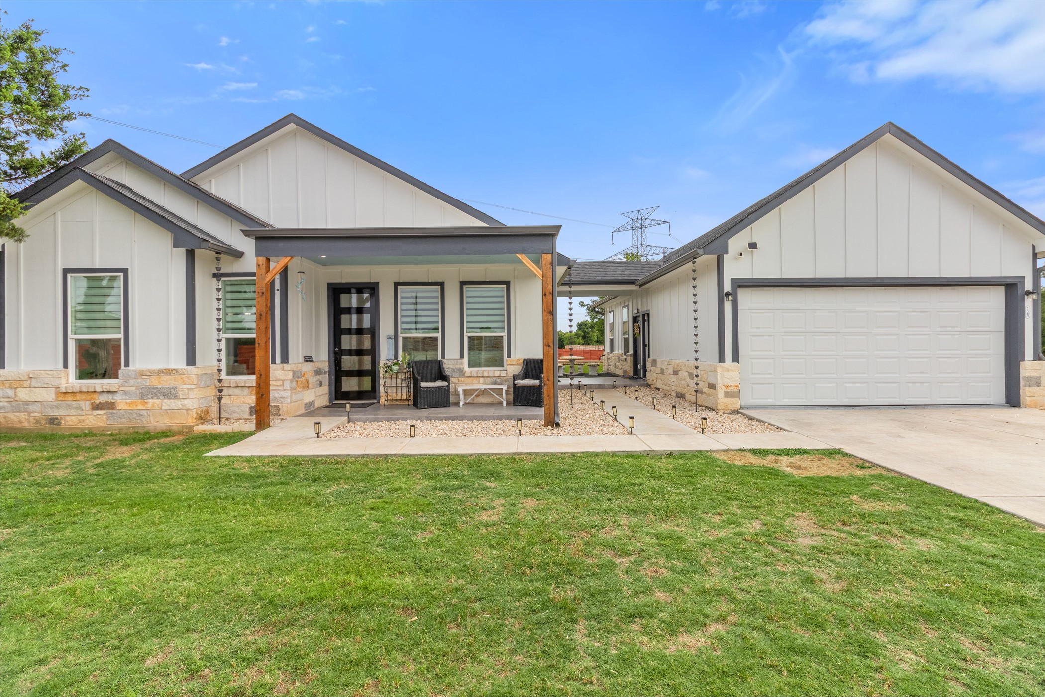 Modern farmhouse exterior featuring board and batten siding, stone accents, and a covered porch with wood columns