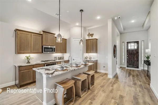 a kitchen with stainless steel appliances a stove a sink dishwasher a refrigerator white cabinets and wooden floor