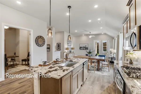 a open kitchen with stainless steel appliances granite countertop a sink stove and a refrigerator with wooden floor