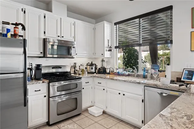 a kitchen with granite countertop a sink stainless steel appliances and white cabinets