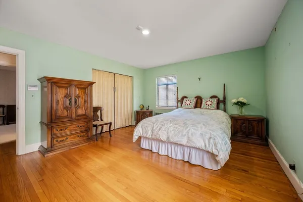a spacious bedroom with a bed and wooden floor