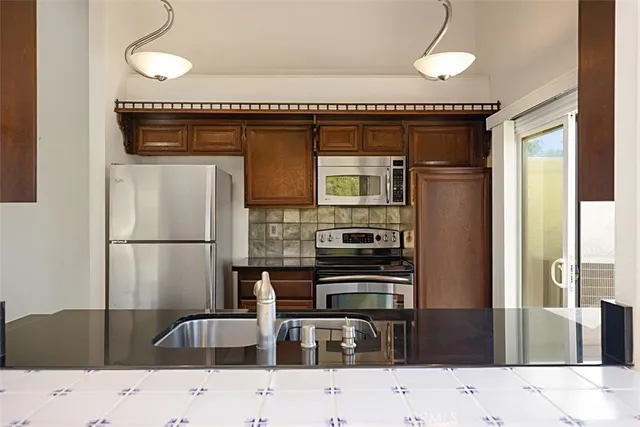 a kitchen with granite countertop a refrigerator and a stove top oven