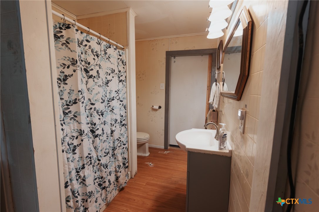 200 Williams Street Cuero, TX 77954 - Photo 10 of 17 a bathroom with a sink and mirror with toilet