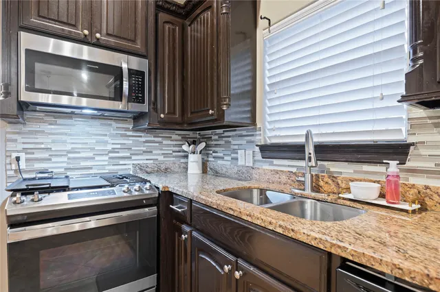 a kitchen with granite countertop a sink stainless steel appliances and cabinets