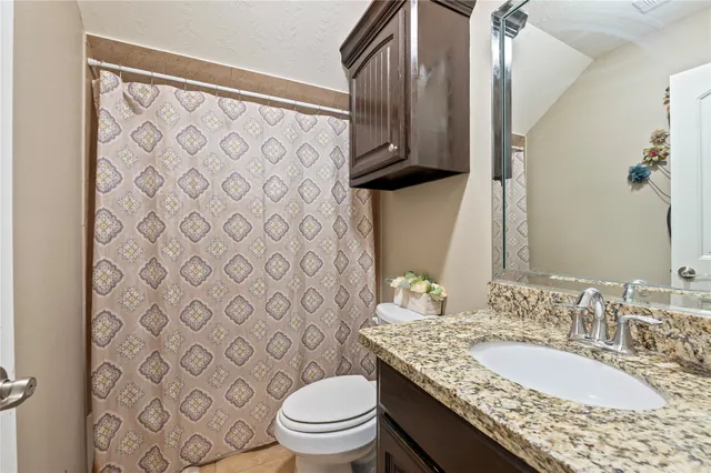 a bathroom with a granite countertop toilet sink and mirror