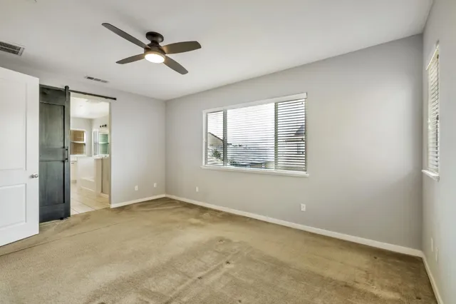 an empty room with ceiling fan and windows