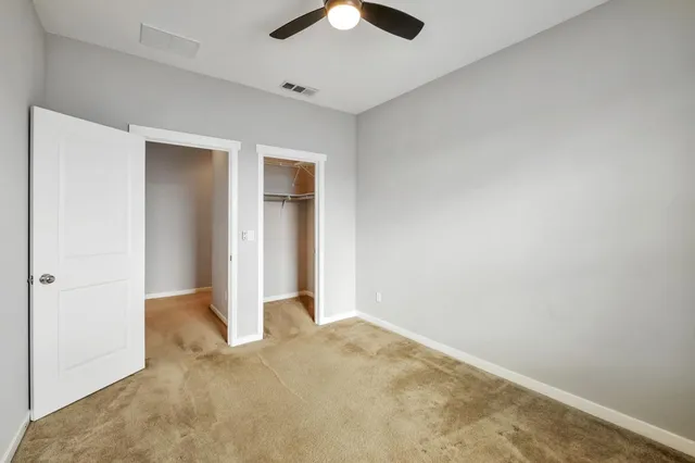 an empty room with closet and a chandelier fan