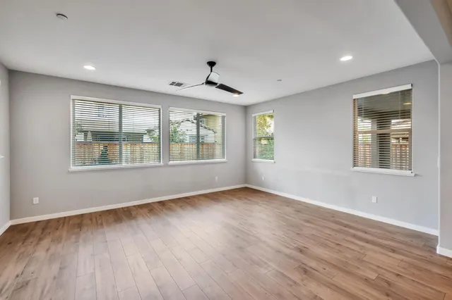 a view of an empty room with wooden floor and windows