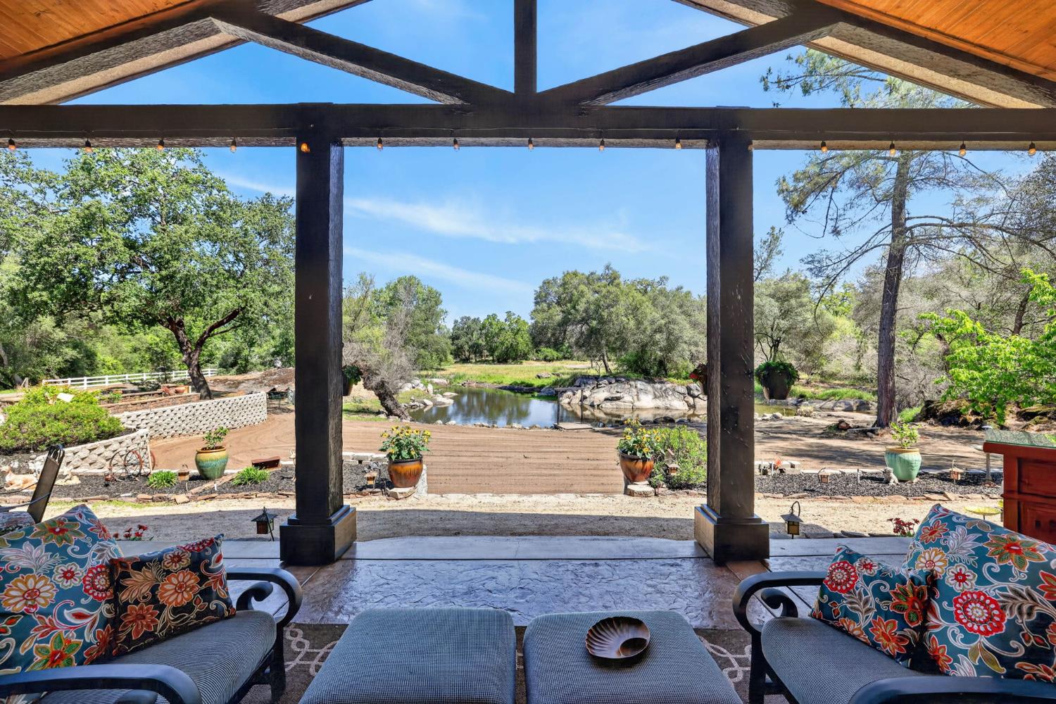 7021 Horseshoe Bar Road Loomis, CA 95650 - Photo 51 of 77 Covered patio with stamped concrete flooring, featuring exposed wood beams and string lighting overlooking the acreage.