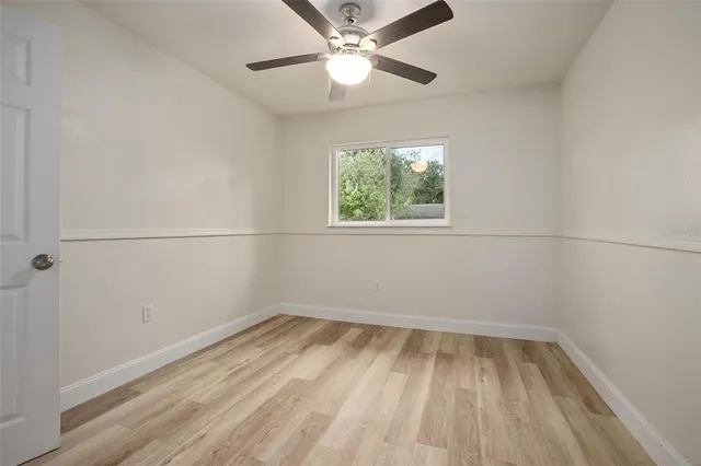 an empty room with a window and a ceiling fan