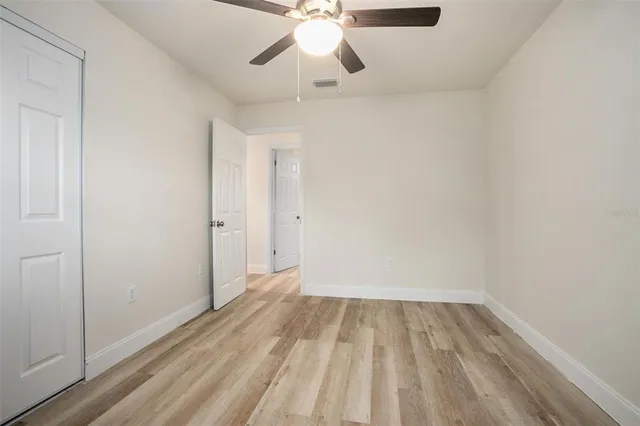 a view of a room with wooden floor a ceiling fan and window