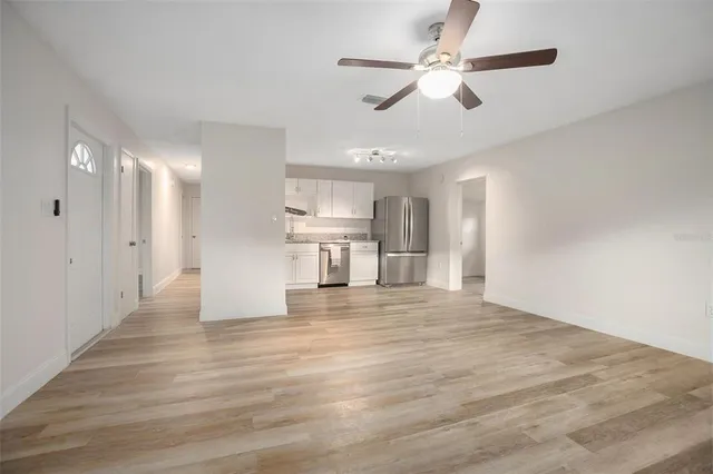 a view of empty room with wooden floor and ceiling fan
