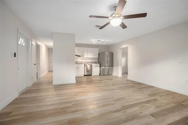 a view of empty room with wooden floor and ceiling fan