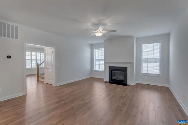 an empty room with wooden floor fireplace and windows