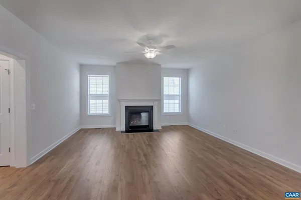an empty room with wooden floor fireplace and windows