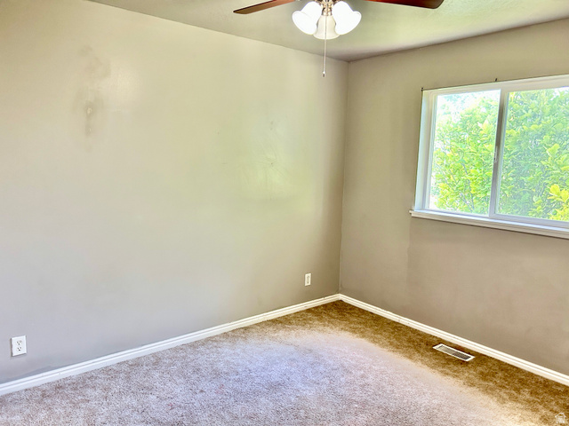672 West 720 South Logan, UT 84321 - Photo 12 of 15 Neutral-toned room featuring a large window, carpet flooring, a ceiling fan with integrated lighting, and white baseboards