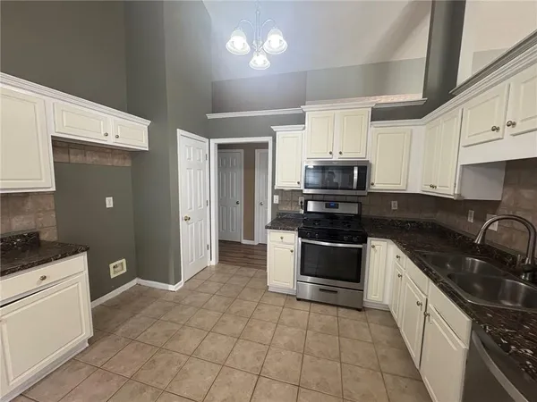 a kitchen with stainless steel appliances a refrigerator a stove a sink a microwave and dining table