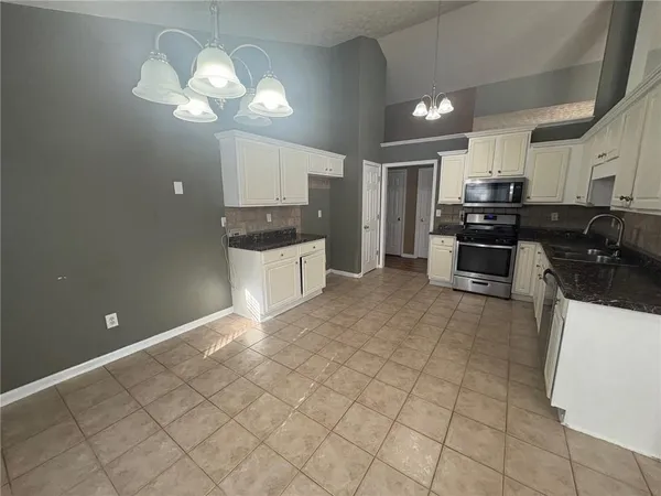 a open kitchen with granite countertop a stove sink and cabinets