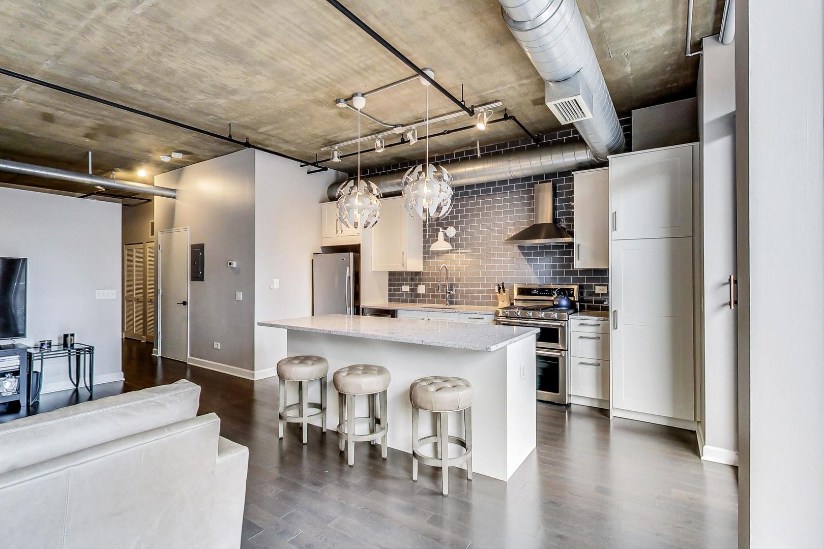 111 South Morgan Street, Unit 522 Chicago, IL 60607 - Photo 22 of 37 a kitchen with stainless steel appliances granite countertop a table chairs in it and wooden floors