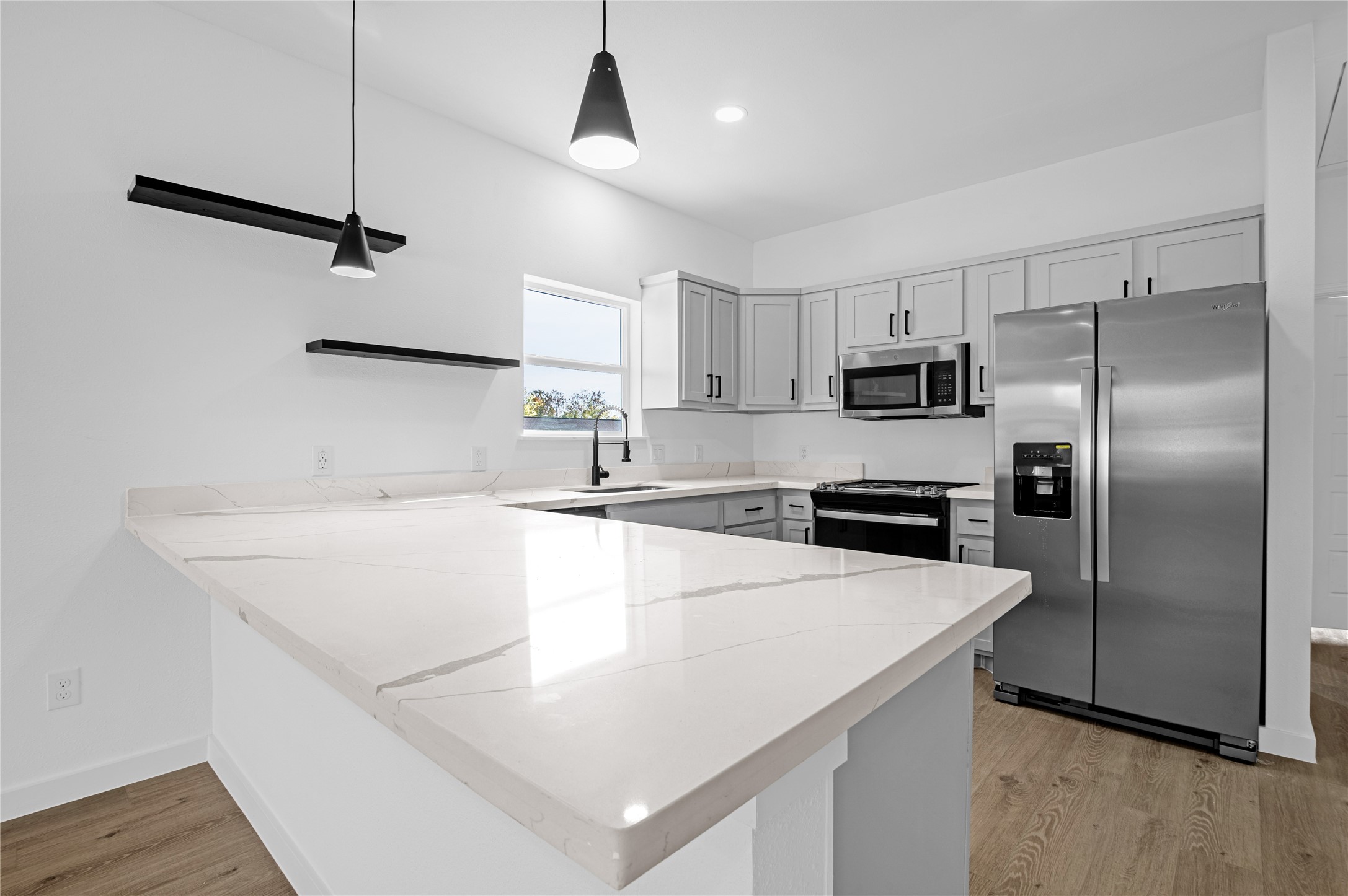 a kitchen with stainless steel appliances a sink a stove a refrigerator with white cabinets and wooden floor