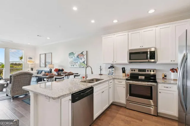 a kitchen with stainless steel appliances granite countertop a refrigerator a stove a sink and a microwave