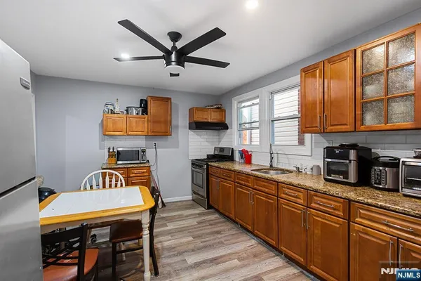 a kitchen with stainless steel appliances granite countertop wooden floors a stove a sink dishwasher a dining table and chairs with wooden floor