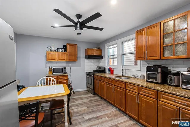 a kitchen with stainless steel appliances granite countertop wooden floors a stove a sink dishwasher a dining table and chairs with wooden floor