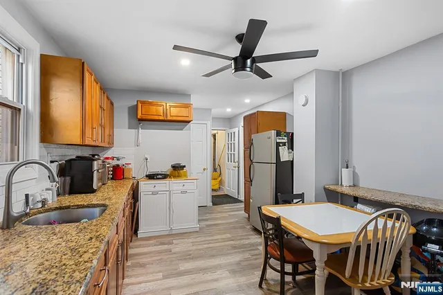 a kitchen with stainless steel appliances kitchen island granite countertop a dining table chairs and a refrigerator