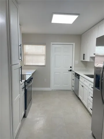 a kitchen with white cabinets and refrigerator