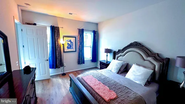 a bedroom with a bed and a dresser with wooden floor