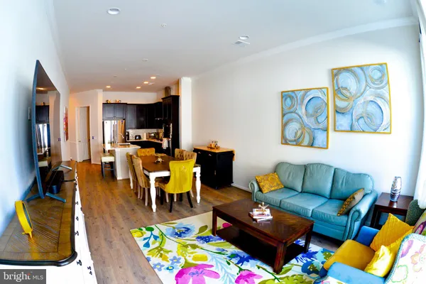 a kitchen with stainless steel appliances kitchen island granite countertop a dining table chairs and a refrigerator