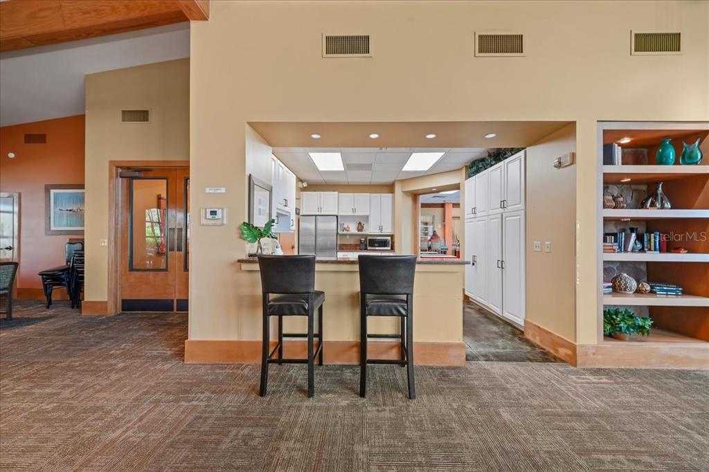 4555 Southwest 52nd Circle, Unit 106 Ocala, FL 34474 - Photo 58 of 100 a open kitchen with stainless steel appliances kitchen island granite countertop a refrigerator a stove a dining table and chairs with wooden floor