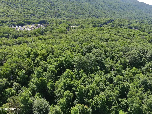 an aerial view of residential house with outdoor space and trees all around
