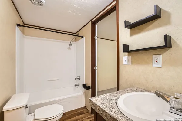 a bathroom with a granite countertop sink toilet and shower