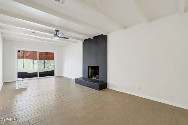 a view of an empty room with wooden floor a fireplace and a window