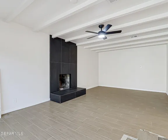 a view of an empty room with a fireplace and a fan