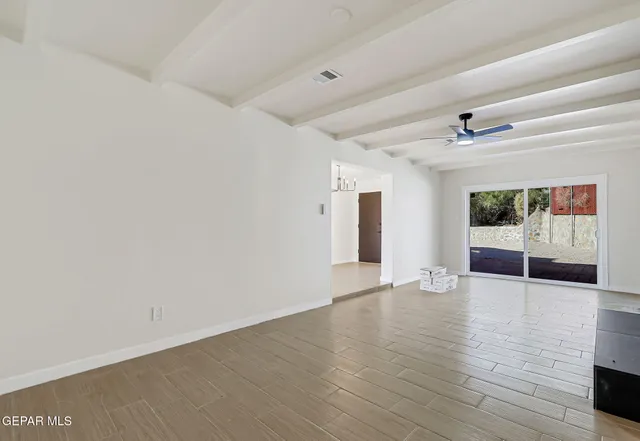 a view of an empty room with a window and wooden floor