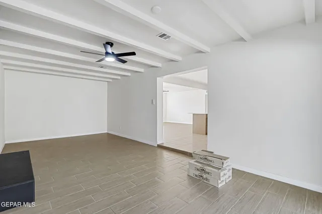 a view of empty room with wooden floor and ceiling fan