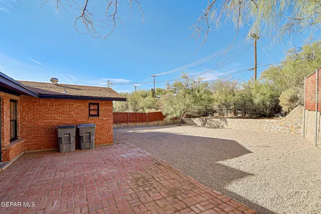 a view of a backyard with plants and brick wall