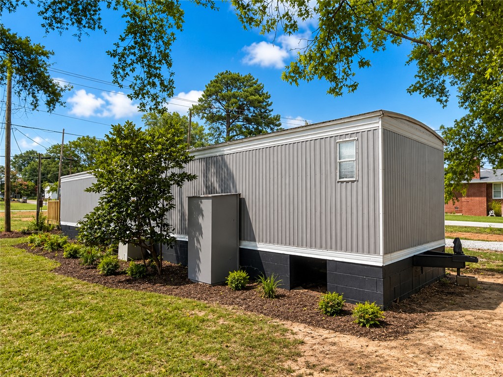 3301 Dixon Road Anderson, SC 29625 - Photo 18 of 20 A well-maintained manufactured home sits neatly on its lot, featuring fresh landscaping and a clear, open sky overhead.