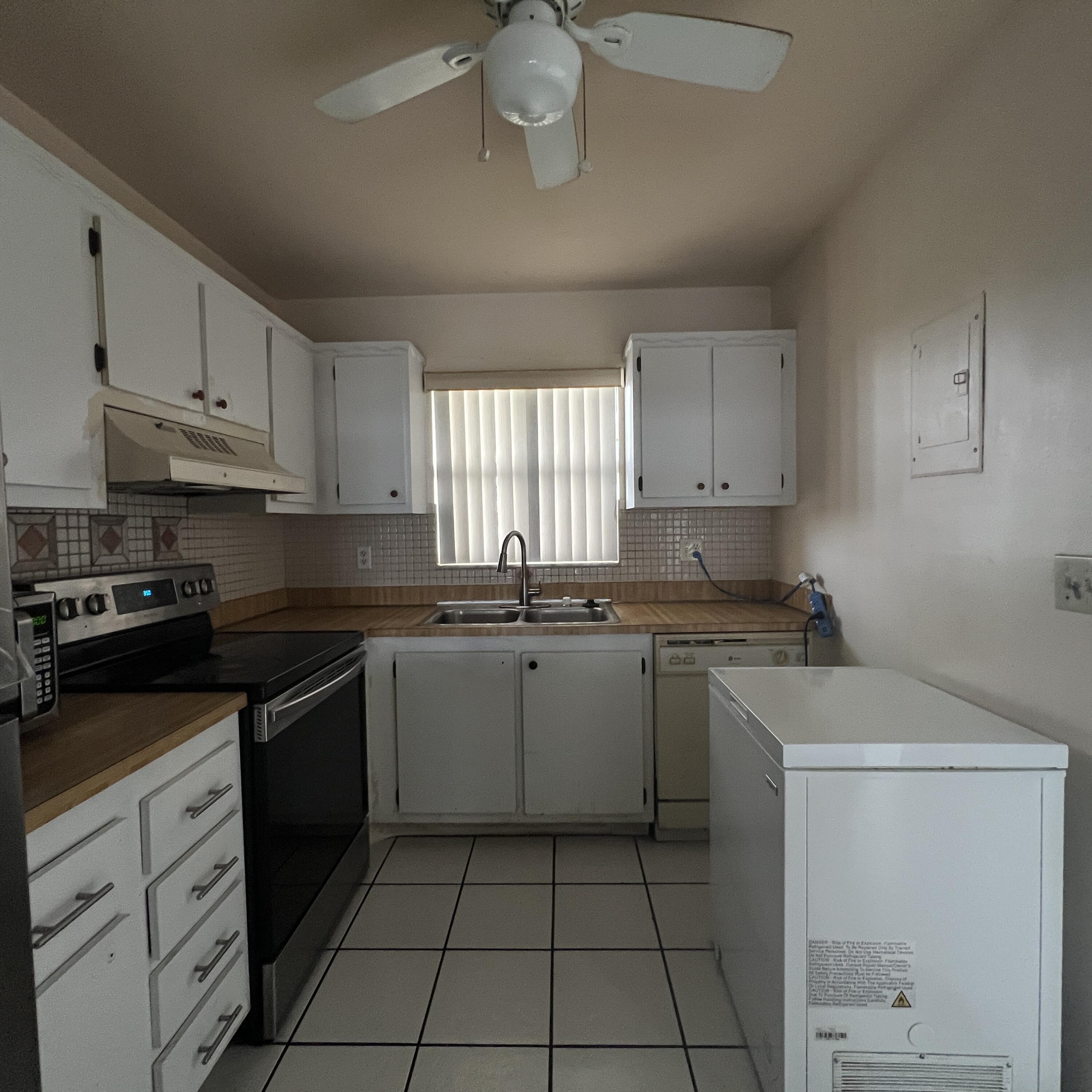 2141 Woolbright Road, Unit L204 Boynton Beach, FL 33426 - Photo 5 of 18 a kitchen with a sink dishwasher a stove and white cabinets