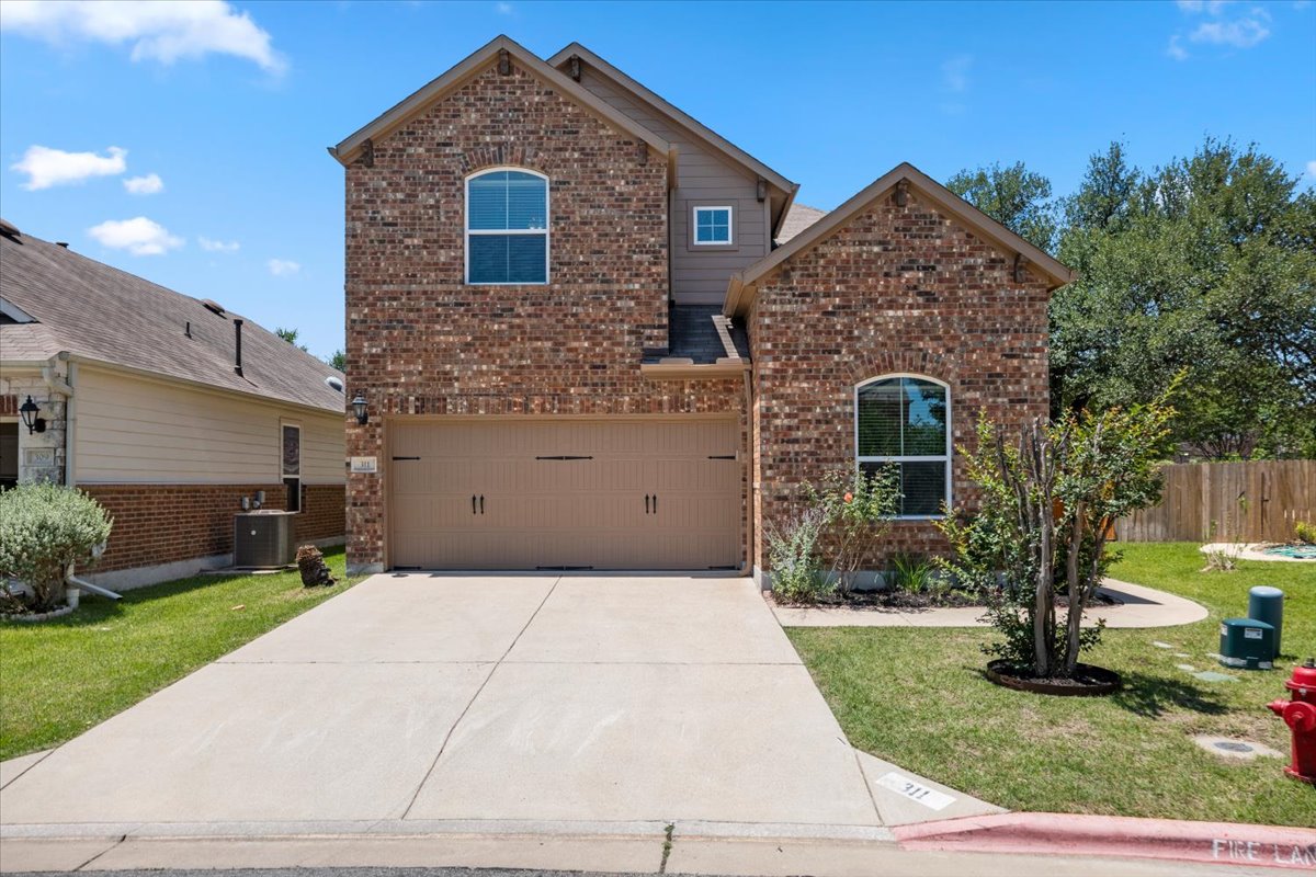 3451 Mayfield Ranch Boulevard, Unit 311 Round Rock, TX 78681 - Photo 1 of 40 Brick facade home featuring a two-car garage, concrete driveway, and established landscaping