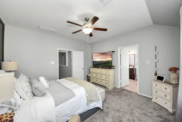a bedroom with a bed and a flat tv screen on dresser